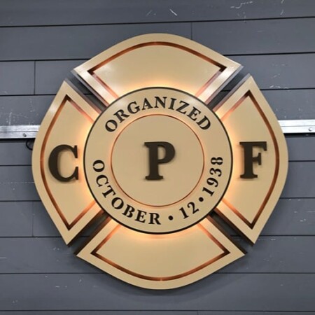 CPF Maltese cross badge sign in cream and bronze reading Organized October 12 1938, glowing warm white.