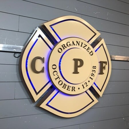 CPF Maltese cross badge sign in cream and bronze reading Organized October 12 1938, glowing blue.