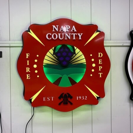 Angwin Volunteer Fire Department Maltese cross badge custom sign for Napa County, grapes and vineyard rows above crossed axes and the date 1932.