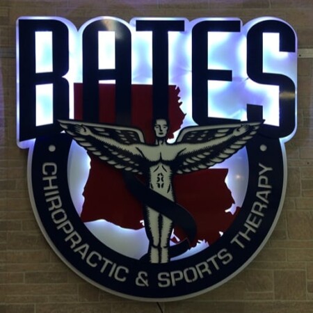 Bates Chiropractic and Sports Therapy sign with a winged figure over a state outline, lit by a white LED halo.
