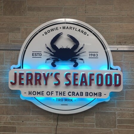 Jerry's Seafood sign for the Home of the Crab Bomb, a blue crab above the name, glowing blue.