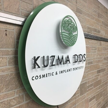 Kuzma DDS sign angled on the stone, the deep green edge return visible behind the white face.
