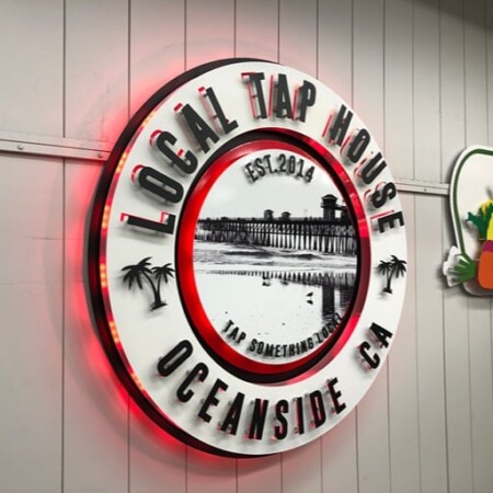 Local Tap House sign angled on the wall, its LED halo glowing red behind the white ring.