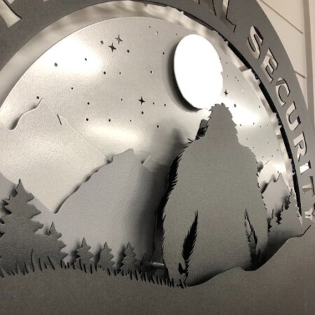 PDX Physical Security round sign with a bigfoot silhouette under the stars above the AWS mark.