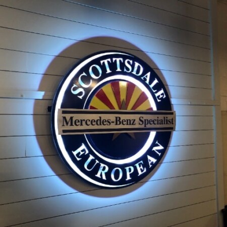 Scottsdale European sign lit, a white LED halo washing out from behind the navy ring.