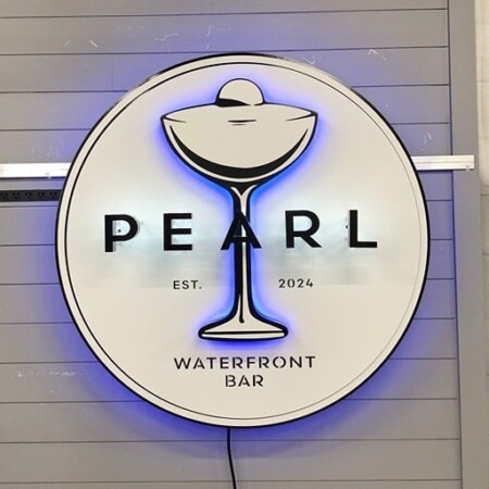 Pearl Waterfront Bar sign lit, a blue LED halo behind the cream disc and the outlined glass.