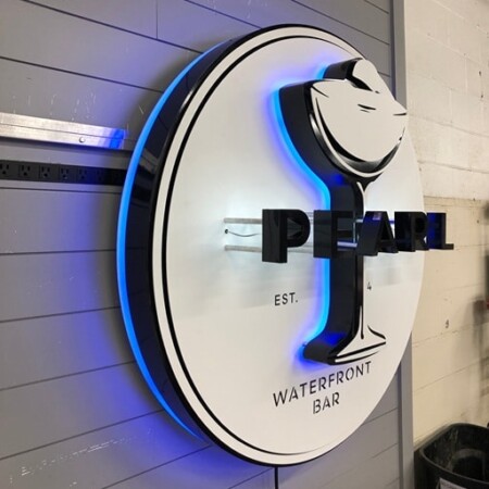 Pearl Waterfront Bar sign angled hard, the blue halo pooling along the edge of the disc.