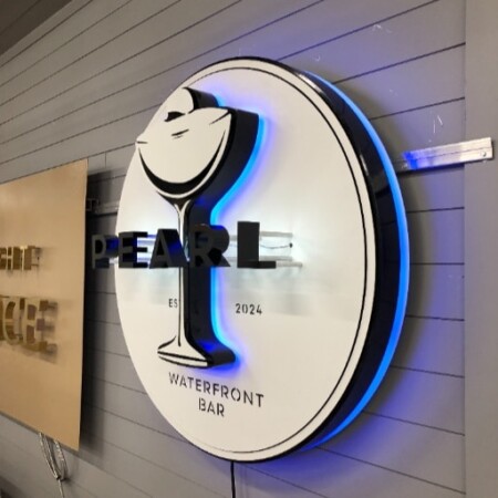 Pearl Waterfront Bar sign from the side, the depth of the disc and its blue glow off the wall.