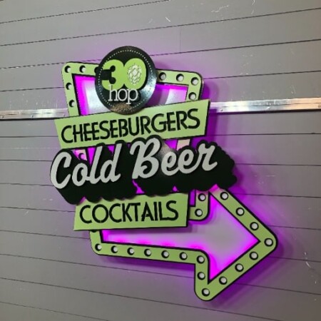 30 Hop layered metal sign with a magenta halo glow, mounted on a corrugated metal wall.