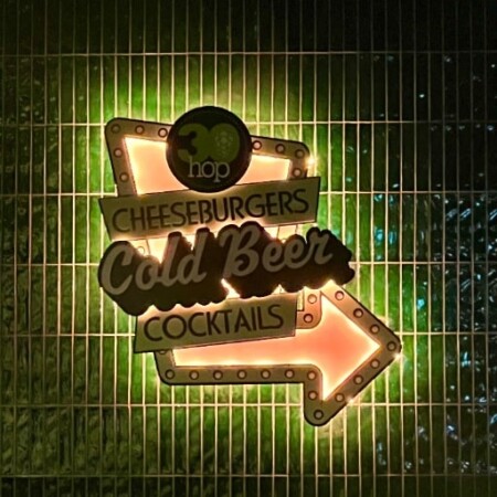 30 Hop bar sign glowing amber and green on a metal grille wall.