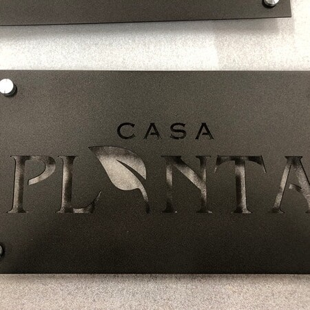 Casa Campos laser-cut plaque sign in dark steel with the name knocked out of the plate, floated on four corner standoffs.