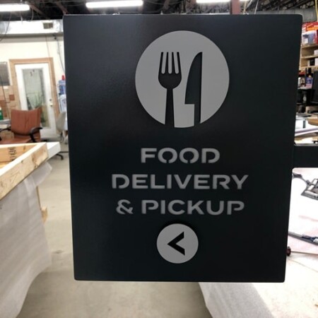 Food Delivery & Pickup wayfinding lightbox and blade sign in charcoal with a fork and knife icon and a direction arrow.