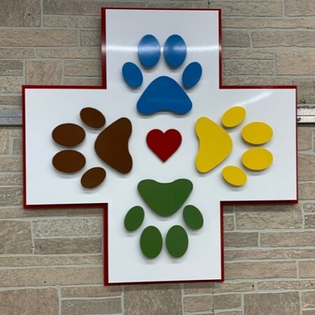 The Integrative Veterinary Clinic cross sign in white and red, paw prints in four colors around a red heart.