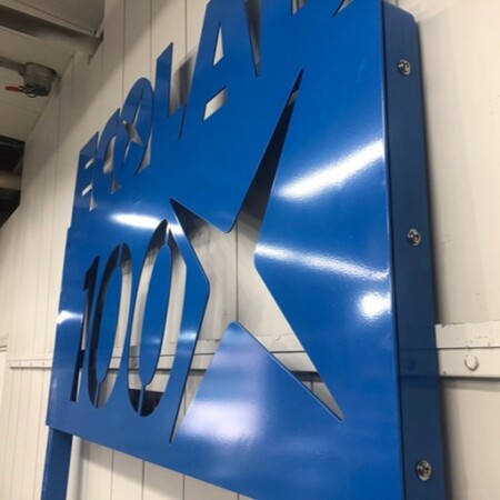 The Ecolab 100 panel from below, the cut star and numerals reading against the wall behind.