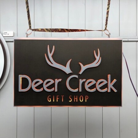 Deer Creek Gift Shop hanging sign in dark brown, antlers above copper and silver lettering.