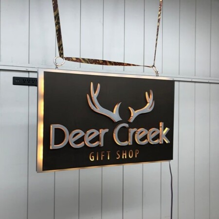 Deer Creek Gift Shop sign hung on chains, angled to show the raised letters and the antler detail.