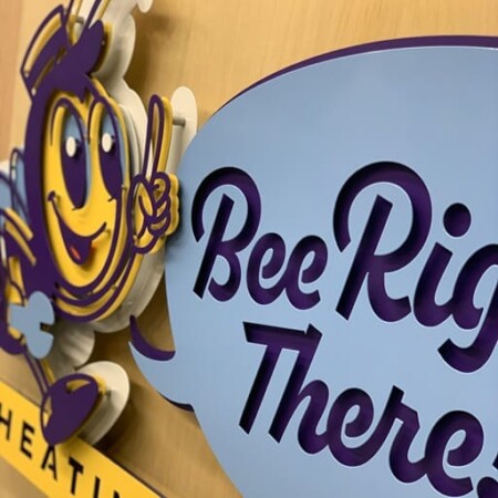 An up-close shot of Bee Right There Heating and Air sign with a cartoon bee pointing to a speech bubble above a yellow banner.