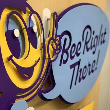 An up-close shot of Bee Right There Heating and Air sign with a cartoon bee pointing to a speech bubble above a yellow banner.