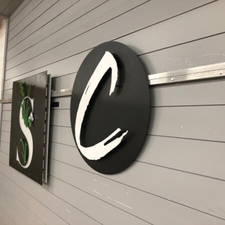Covenant Church round sign in matte black with a white brushstroke C.