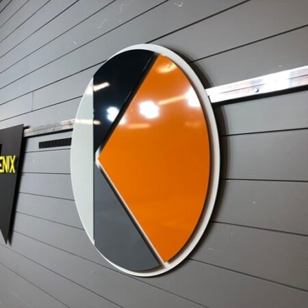 The Moldgenix disc from an angle, the gloss orange and charcoal faces standing off the wall.