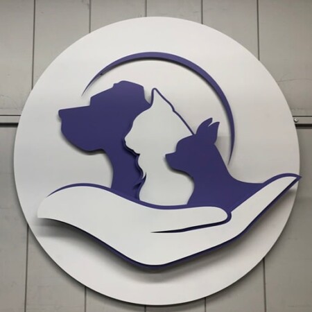 The Neighborhood Vet round sign, a dog and cat silhouette resting in a cupped hand.