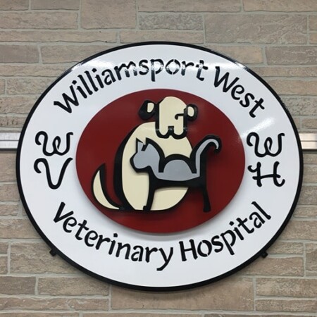 Williamsport West Veterinary Hospital oval sign with a dog and cat inside a red disc, the name curved around it.