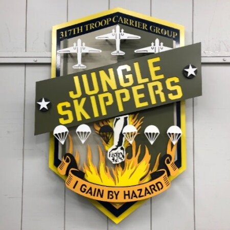 Jungle Skippers 317th Troop Carrier Group patch sign, paratroopers over flames beneath the unit banner.