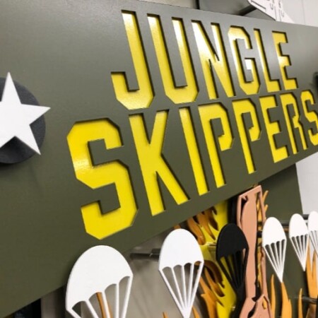 Close view of the Jungle Skippers patch, the yellow banner raised above layered parachutes.