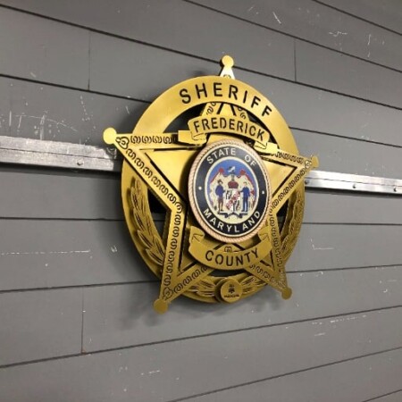 Frederick County Sheriff badge from an angle, the gold star and wreath layers stepping off the wall.