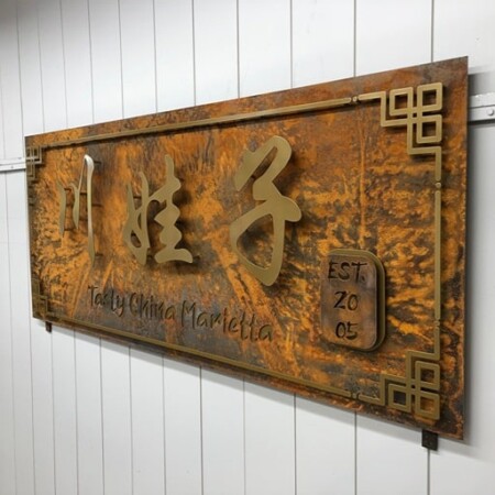 Tasty China Marietta sign on a rusted steel plate, gold Chinese characters above the name and est. 2005.